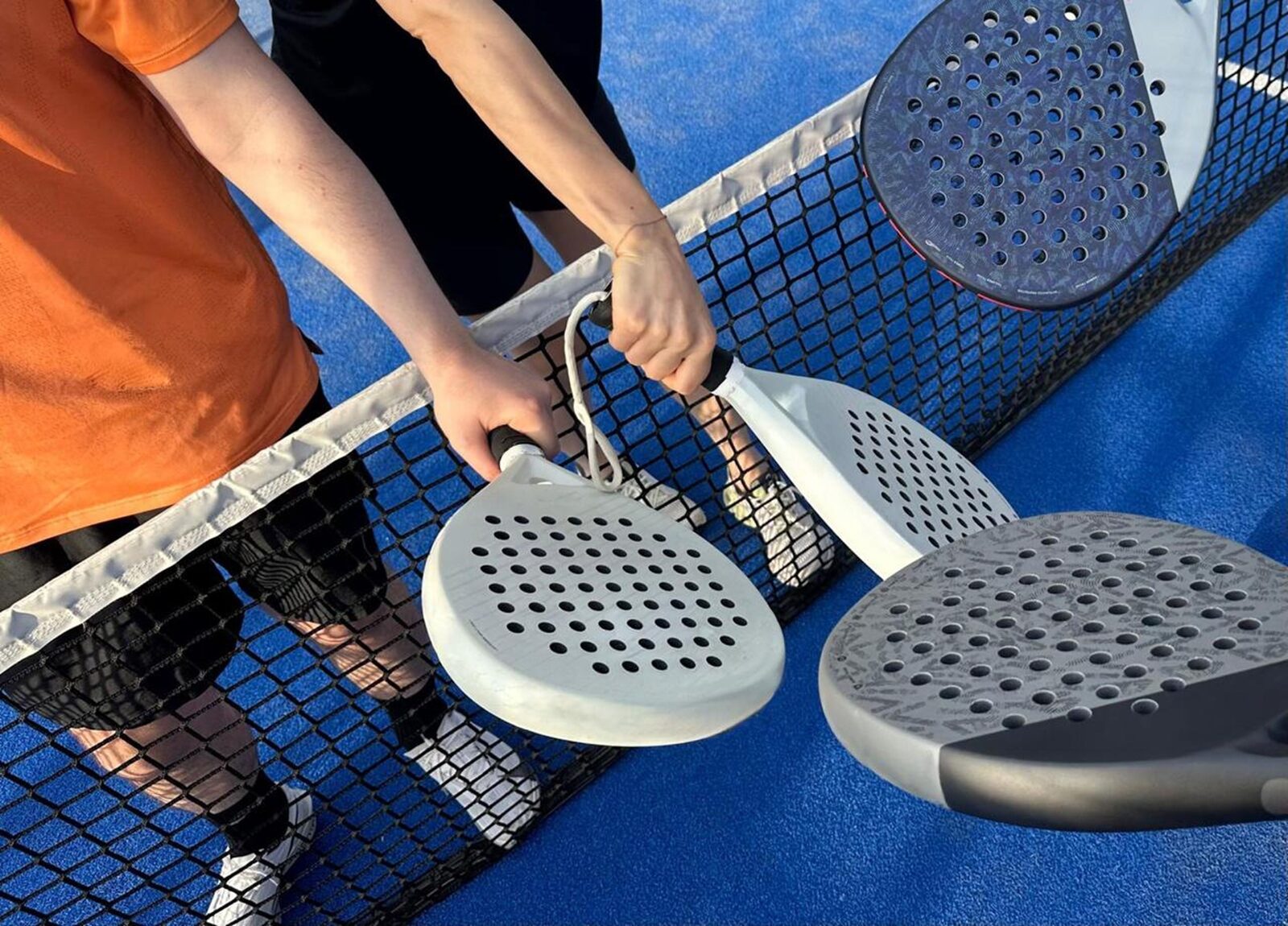 Players tapping rackets over the net at the end of a match